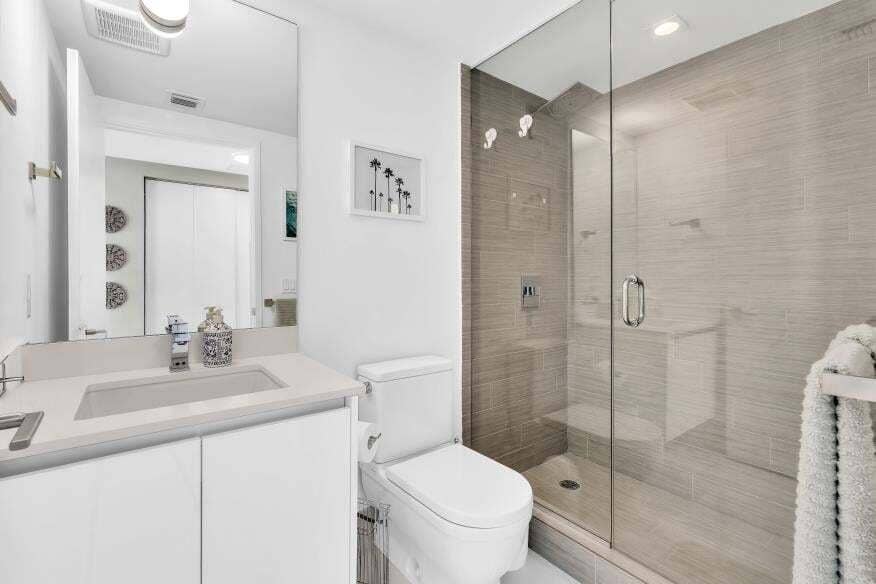 Sunny Isles Beach, Sunny Isles Beach, FL 33160 Modern bathroom featuring a frameless glass shower enclosure, a full-height vanity mirror, a single-sink vanity with white cabinetry, and a walk-in shower with tile surround