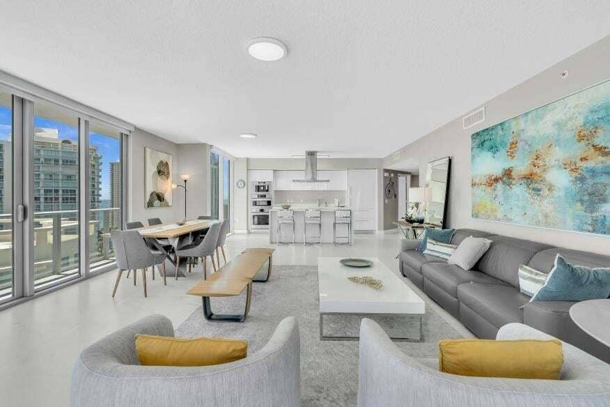 Sunny Isles Beach, Sunny Isles Beach, FL 33160 Open-concept living space with expansive sliding glass doors, white flooring, recessed lighting, and a modern kitchen with built-in appliances