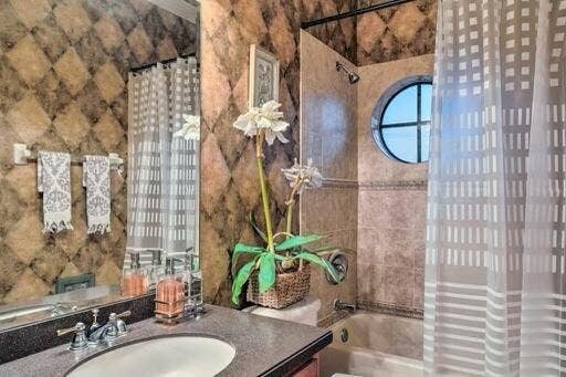Dark-toned countertop with an under-mount sink, chrome faucet, and integrated mirror