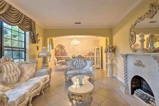Tile flooring, ornate fireplace with mantel, arched doorway, large window, and crown molding