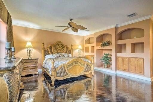 Wood-finish flooring, built-in shelving, integrated cabinetry, ceiling fan, and crown molding