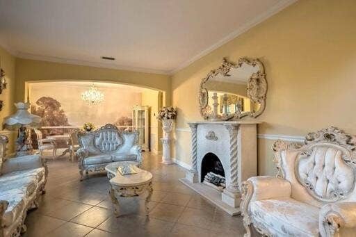 Arched entryway with overhead lighting, prominent fireplace with ornate mantel, and decorative wall mirror