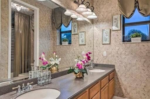 Dual vanity with integrated sinks, ample countertop space, wood-finish cabinetry, and a large mirror