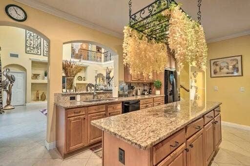 Kitchen featuring wood cabinetry, stone countertops, integrated sink, and an expansive island