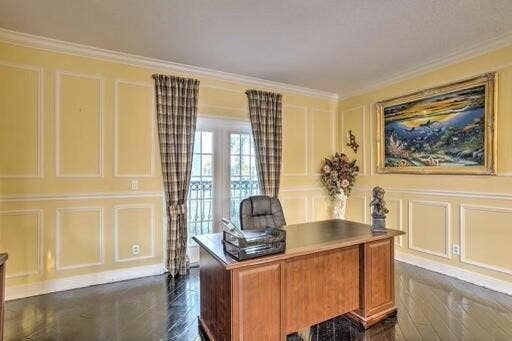 Wainscoting paneling, crown molding, double French doors, and dark wood-finish flooring
