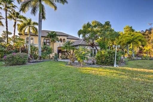 Mediterranean-style architecture with arched windows and a tiled roof, surrounded by mature palm trees and established landscaping