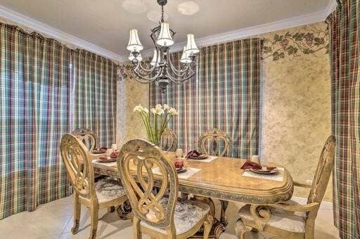 Chandelier lighting fixture with multiple arms, decorative crown molding, and ornate wall detailing