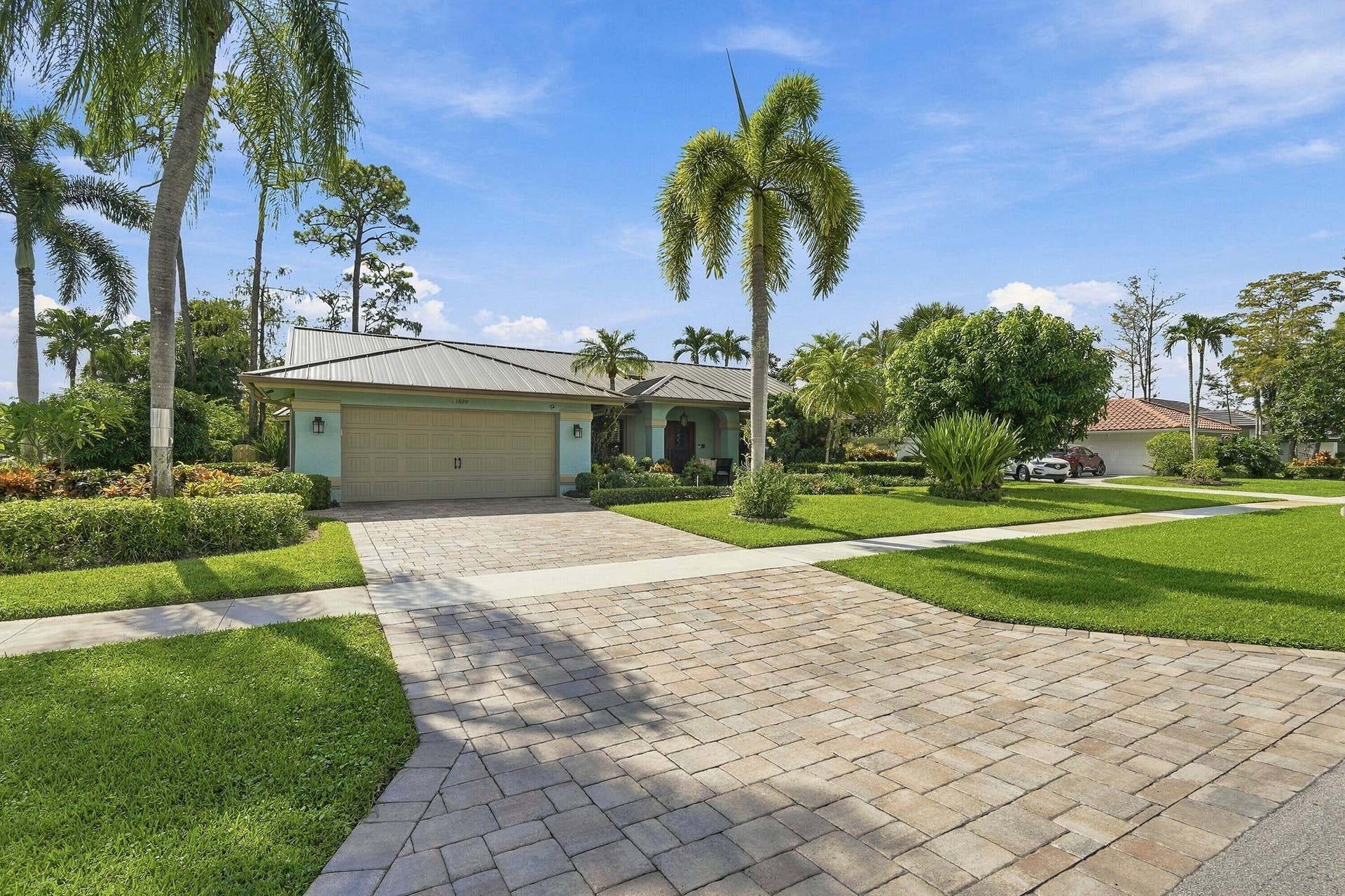 Single-story residence featuring a metal roof, attached two-car garage, and a paver driveway