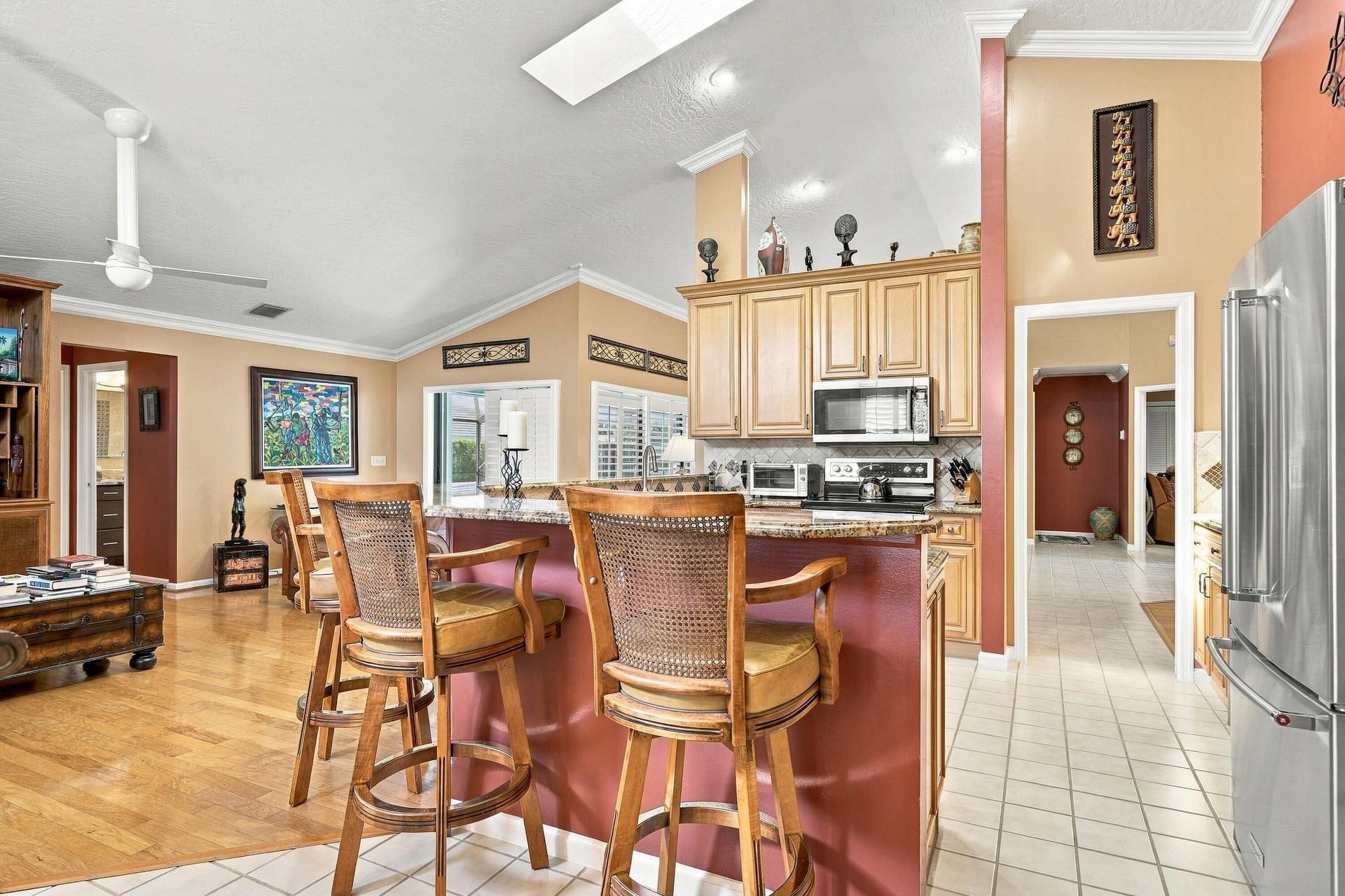 Open-concept kitchen with stainless steel appliances, granite countertops, and light wood cabinetry