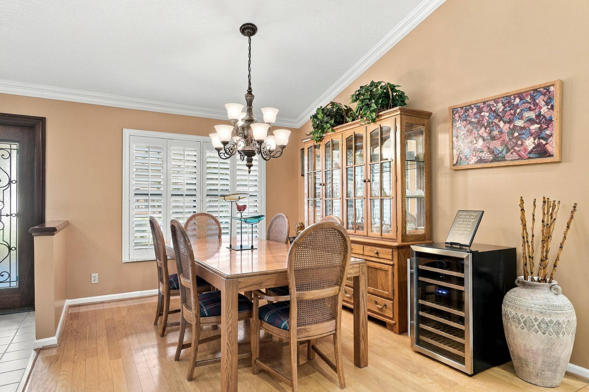 Wood-finish flooring, crown molding, and a chandelier with frosted glass shades