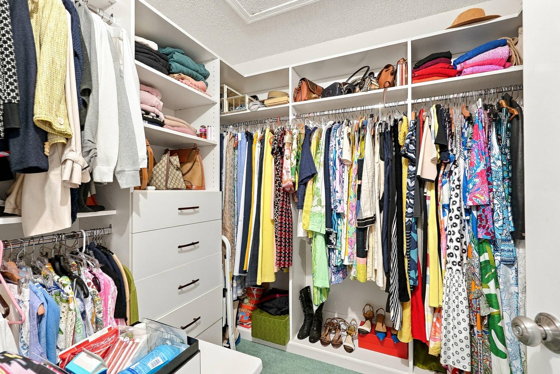 Custom closet system featuring multiple hanging rods, built-in shelving, and drawer storage