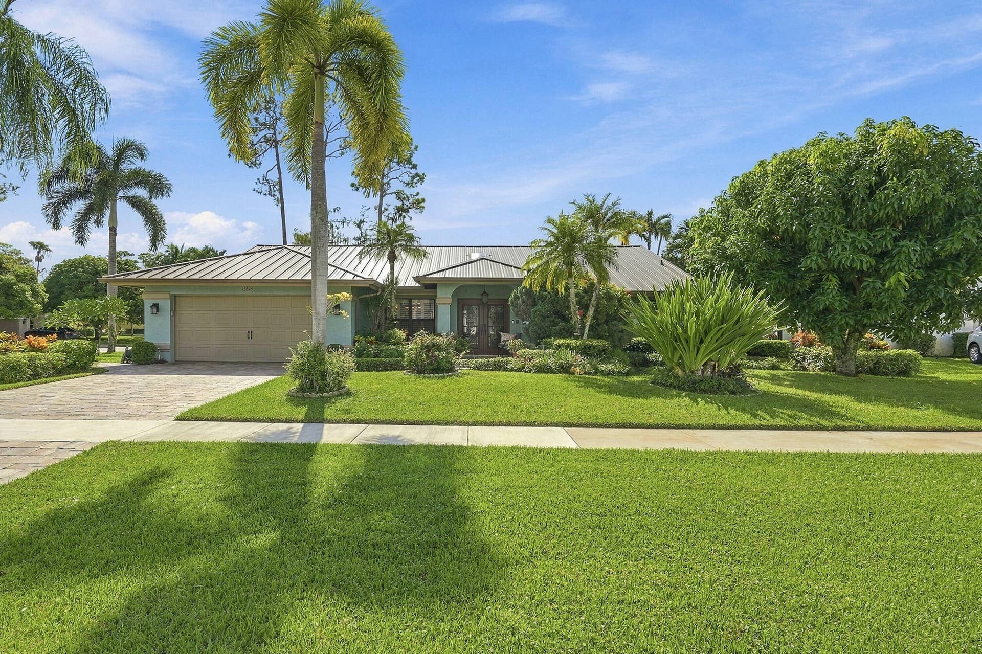 Expansive front lawn with mature tropical landscaping