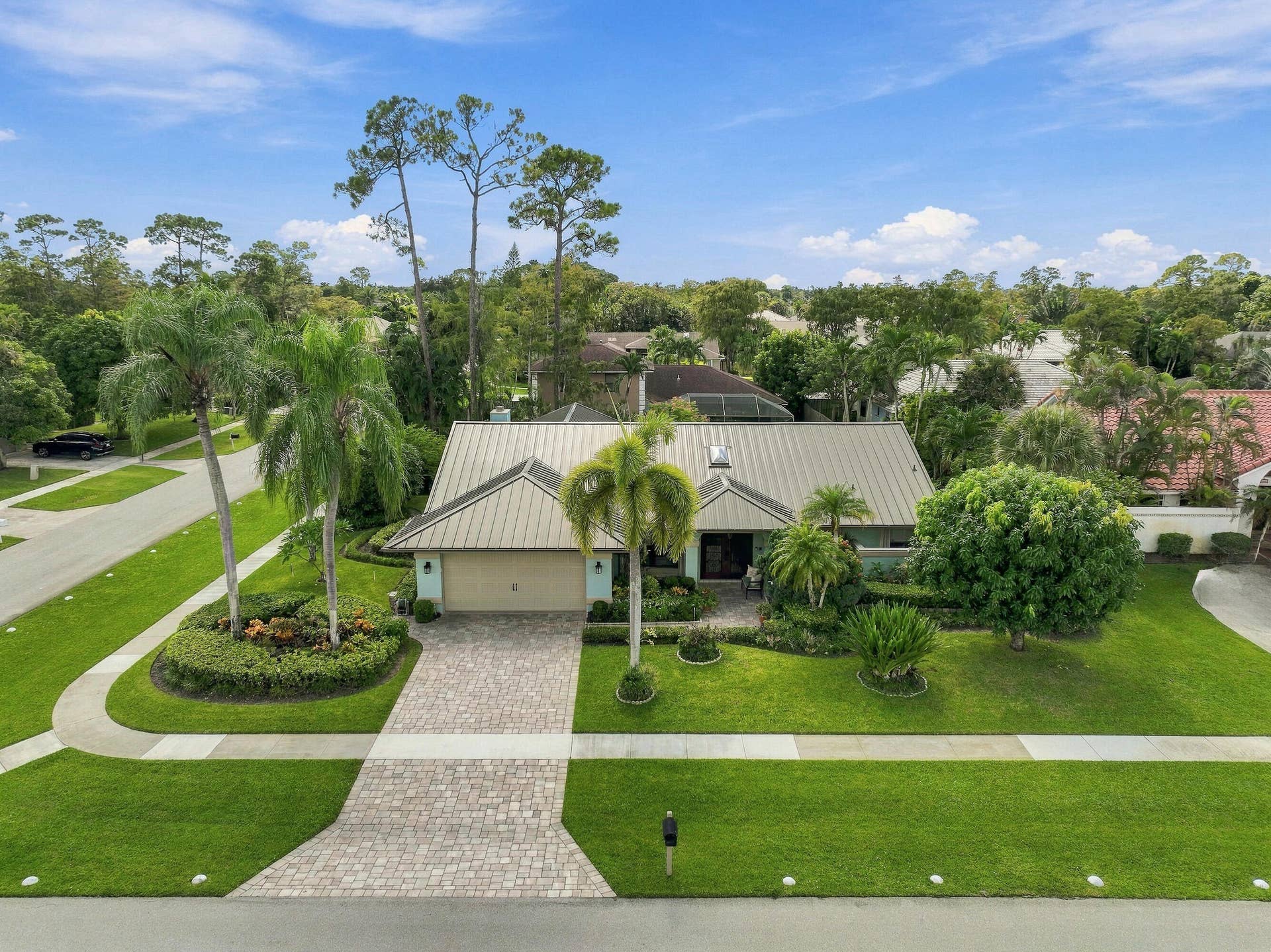 Single-story residence featuring a metal roof, an attached garage, and a paver driveway