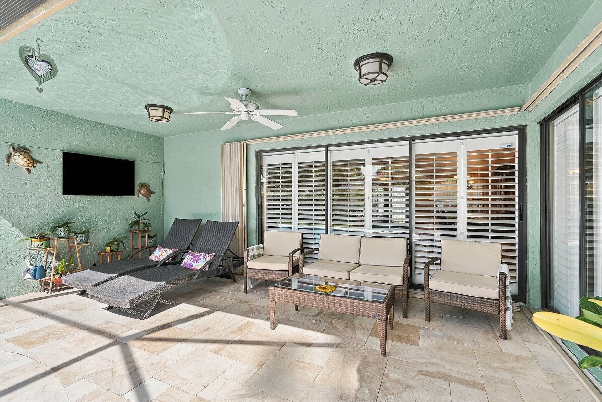 Covered patio featuring a ceiling fan, recessed lighting, and large sliding glass doors with interior shutters