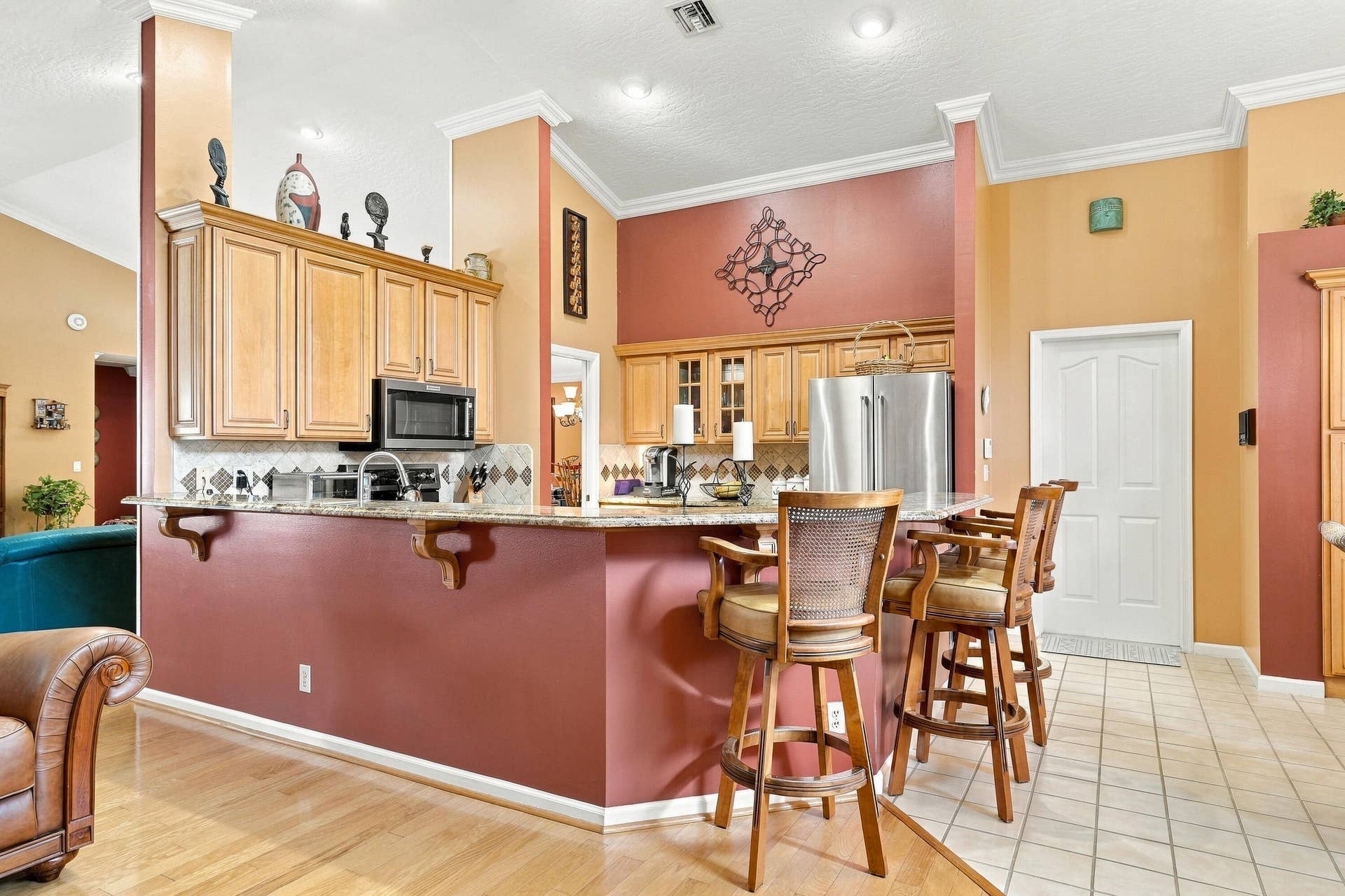 Kitchen featuring granite countertops, wood-finish cabinetry, stainless steel appliances, and a breakfast bar