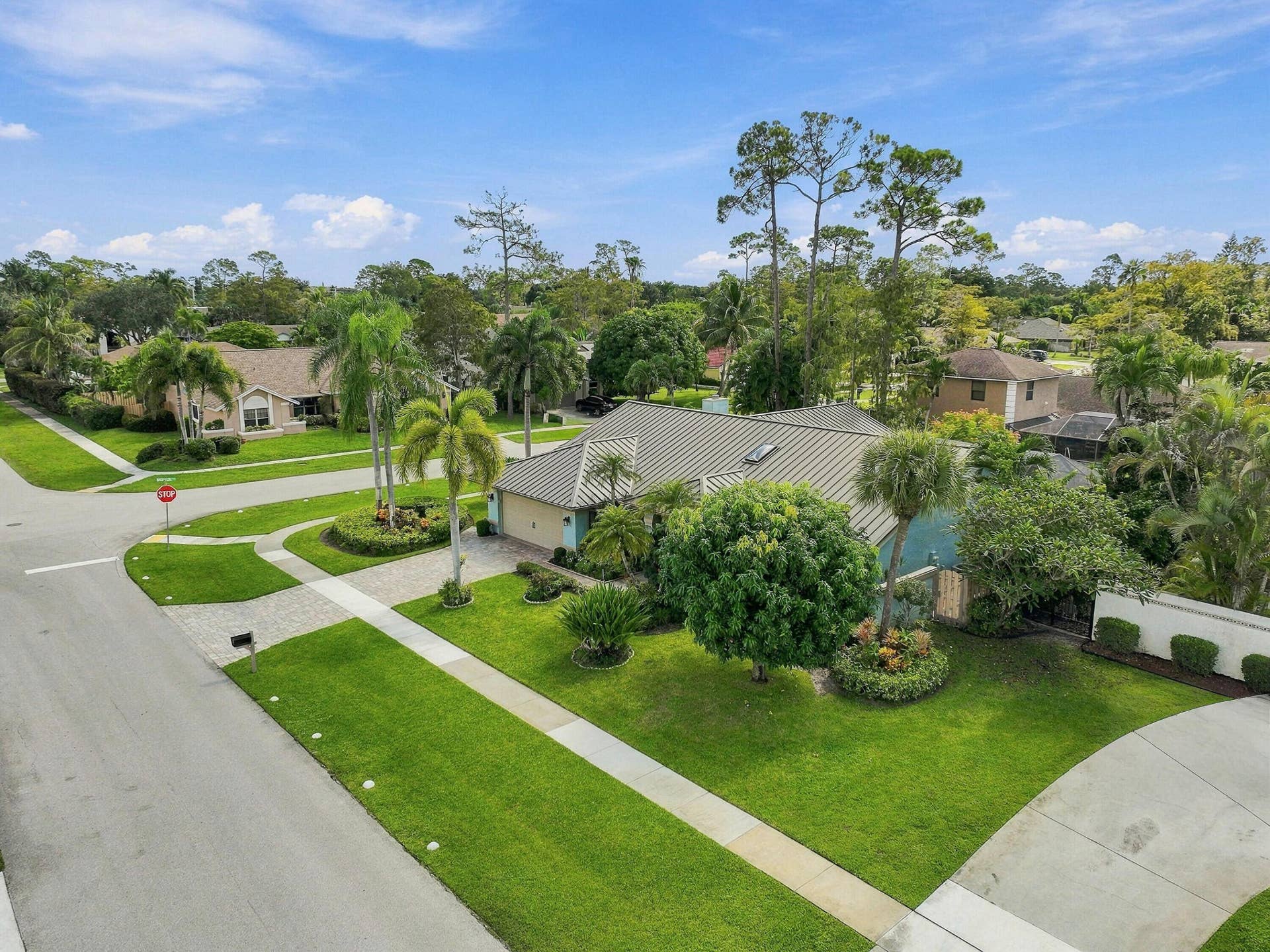 Residential corner lot featuring mature landscaping, a paved driveway, and a well-maintained lawn