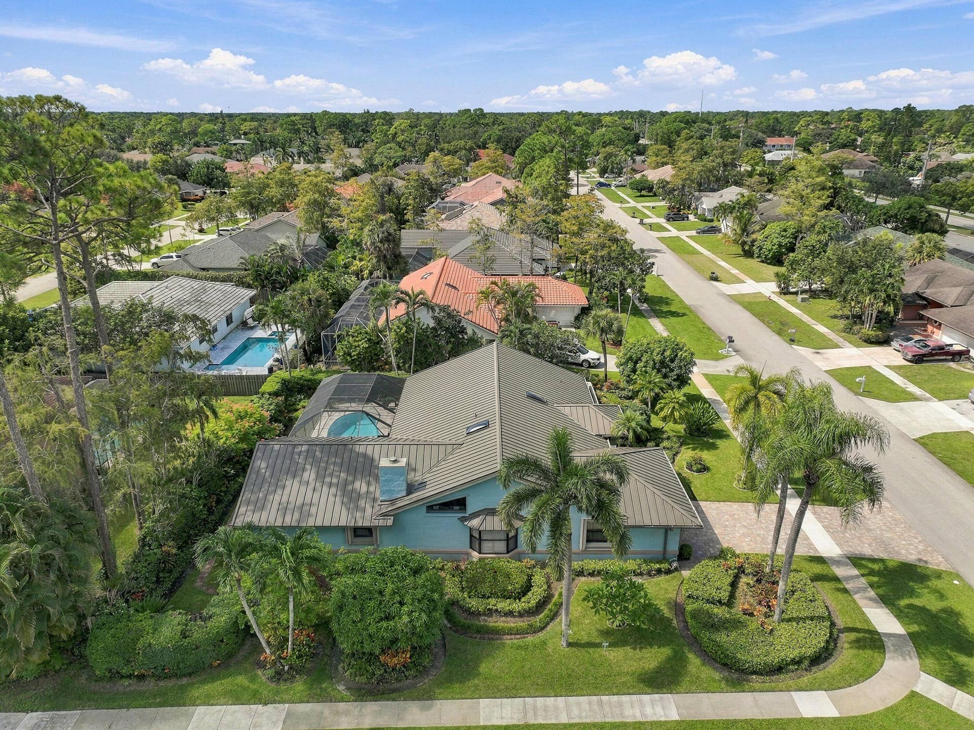 Property featuring a teal exterior, multi-pitched roofline, front yard landscaping, and a circular front driveway