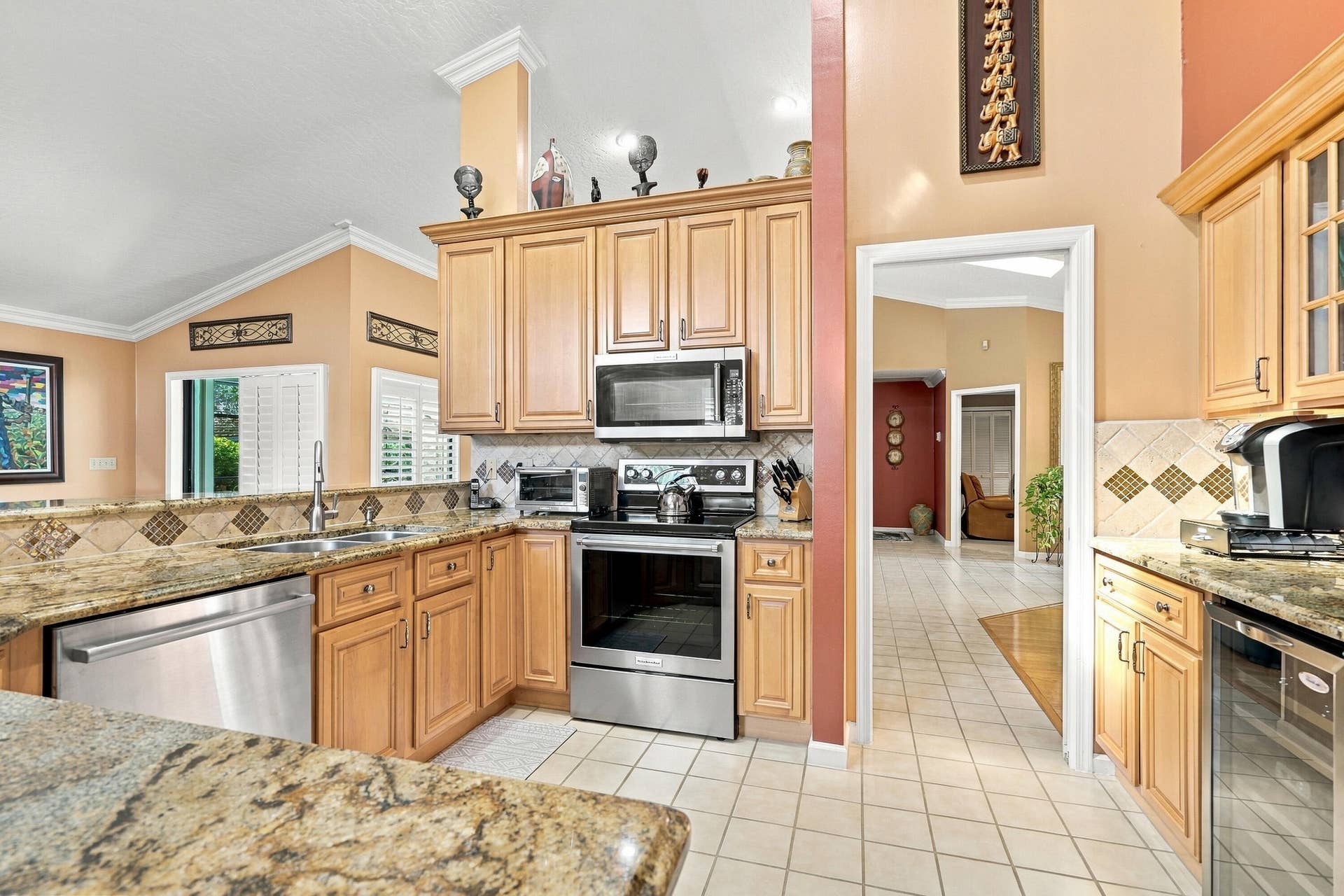Kitchen featuring light wood cabinetry, granite countertops, tile flooring, and stainless steel appliances