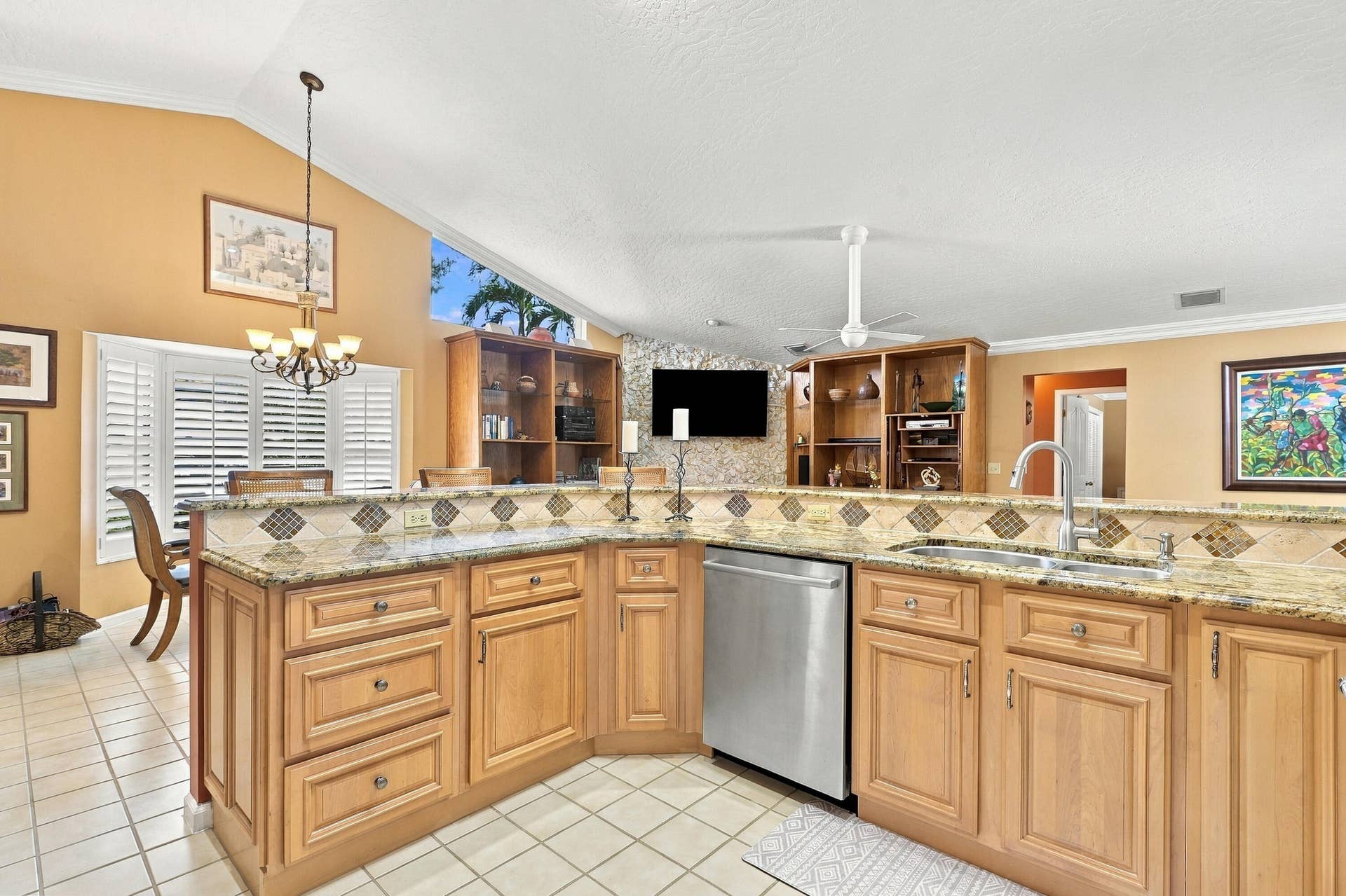 Kitchen featuring granite countertops, wood cabinetry, stainless steel dishwasher, and an undermount sink