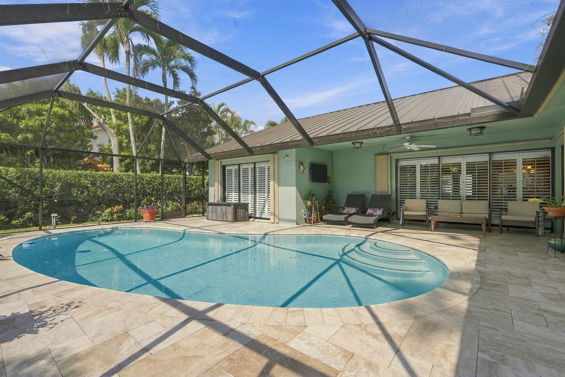 Screened-in outdoor pool featuring an oval shape and integrated steps