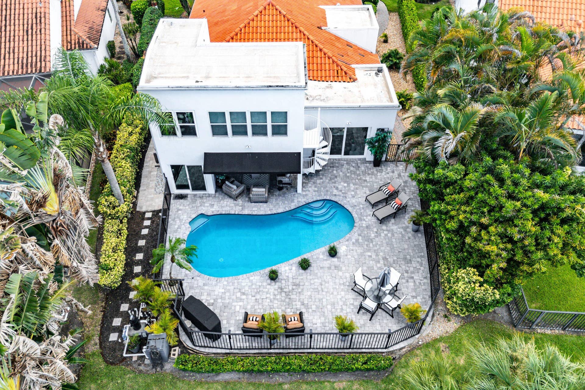 13138 Touchstone Place, Palm Beach Gardens, FL 33418 Contemporary white stucco exterior with a curvilinear pool, extensive paver patio, spiral staircase, and mature tropical landscaping