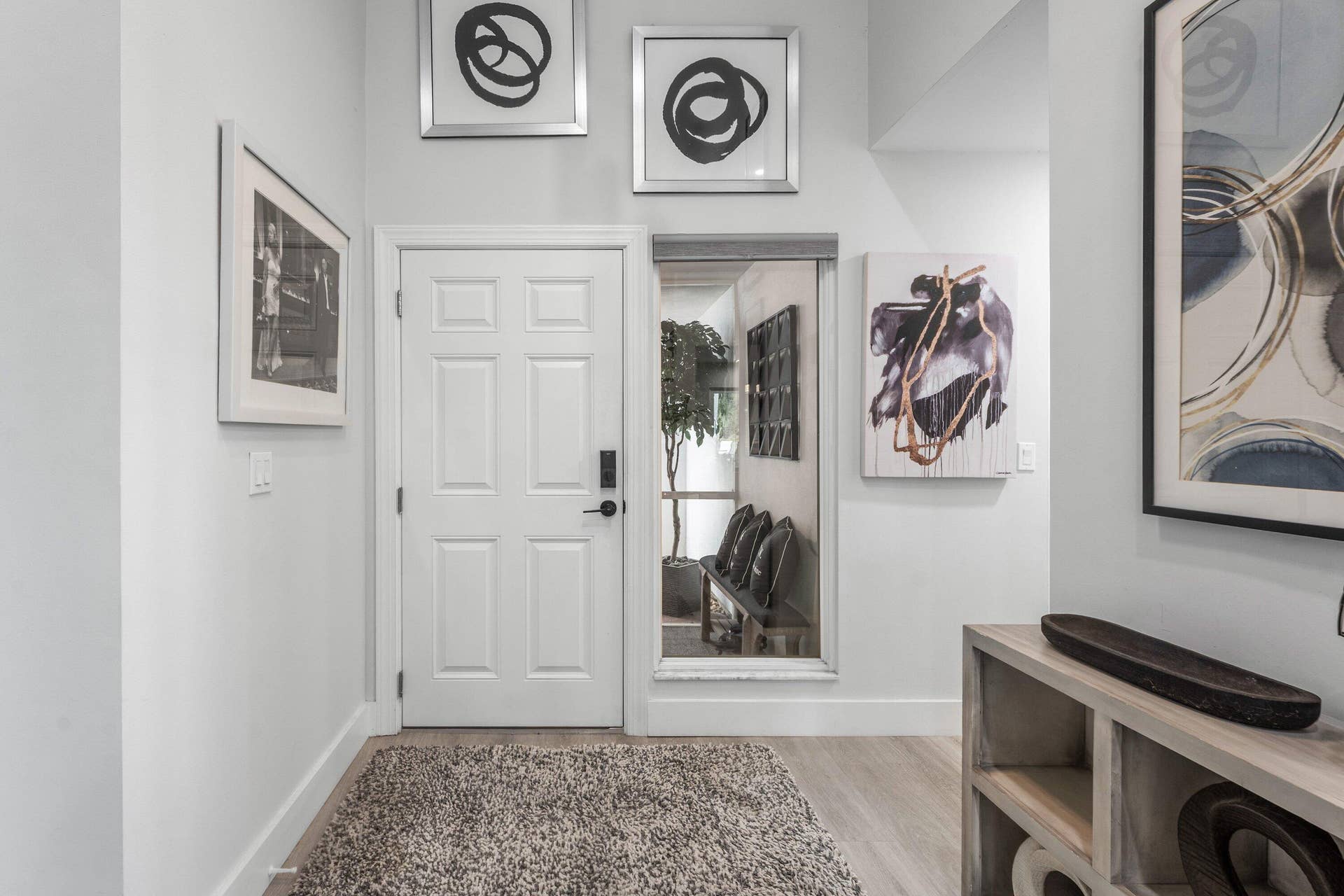 13138 Touchstone Place, Palm Beach Gardens, FL 33418 White paneled entry door with matte black hardware, wood-finish flooring, recessed lighting, and a built-in shelving unit