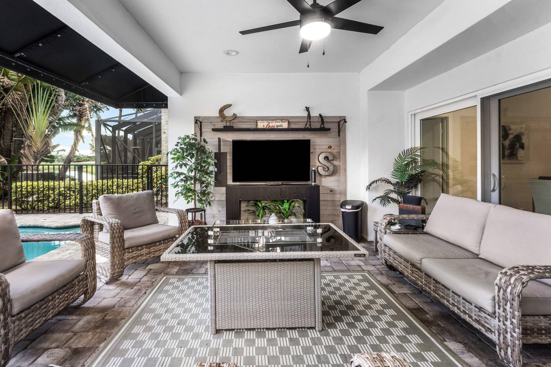 13138 Touchstone Place, Palm Beach Gardens, FL 33418 Covered outdoor living space featuring a ceiling fan, a built-in media wall with shelving, sliding glass doors, and paver flooring
