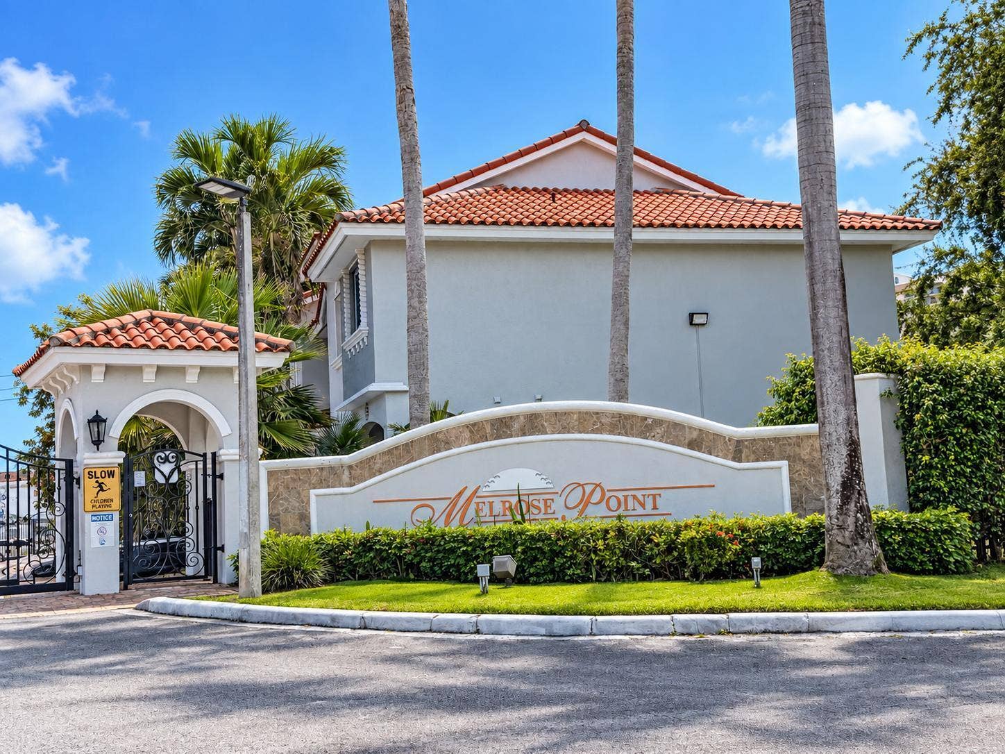 Entry gate featuring an arched stucco entryway, wrought iron gate, and tile roof. Virtually staged.