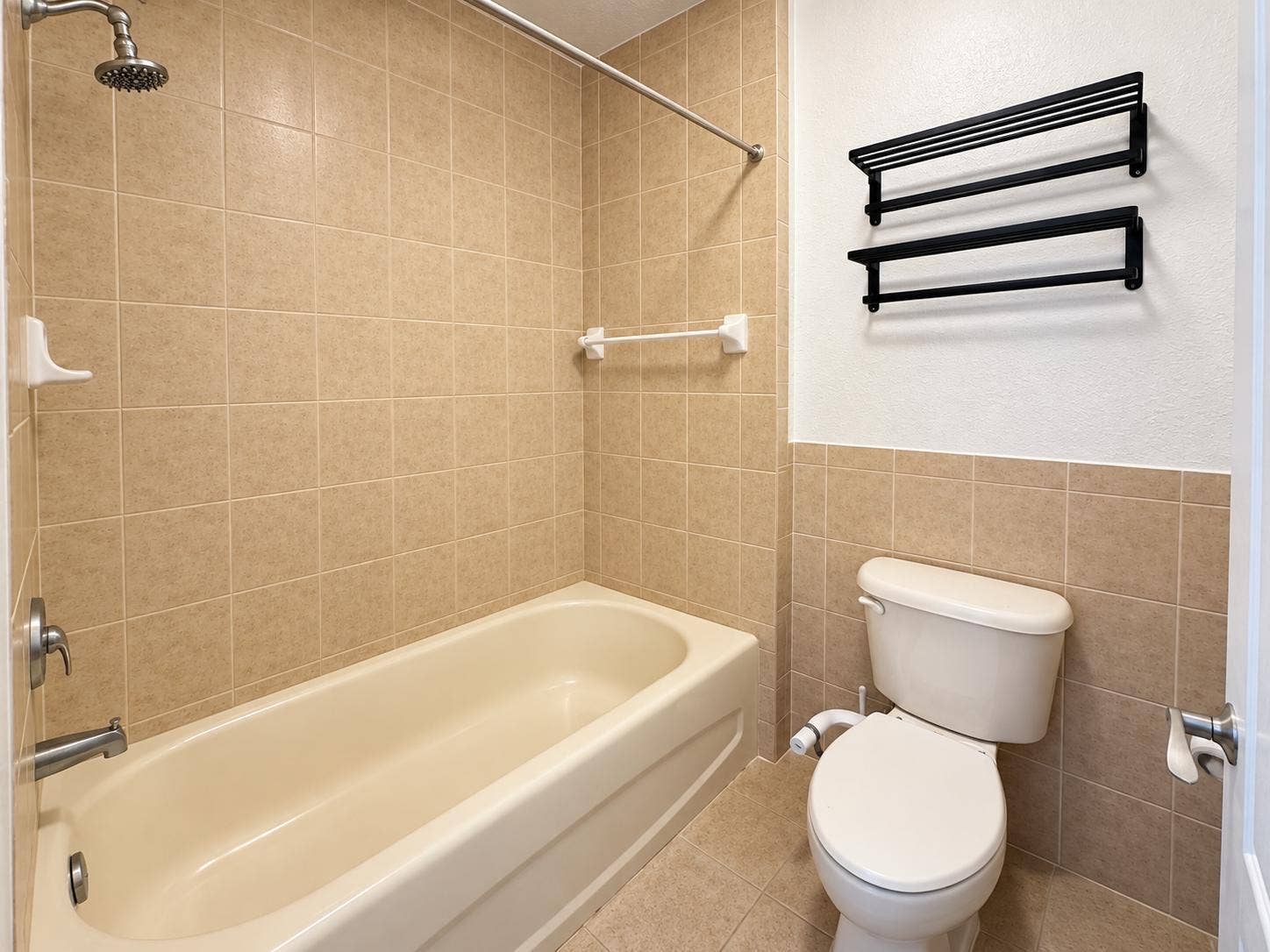 Tiled shower and bath combination with a rain shower head. Virtually staged.