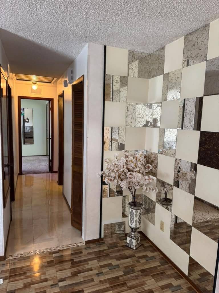 Kissimmee, FL 34744 Hallway featuring wood-finish tile flooring and a wall with decorative mirrored and solid panels