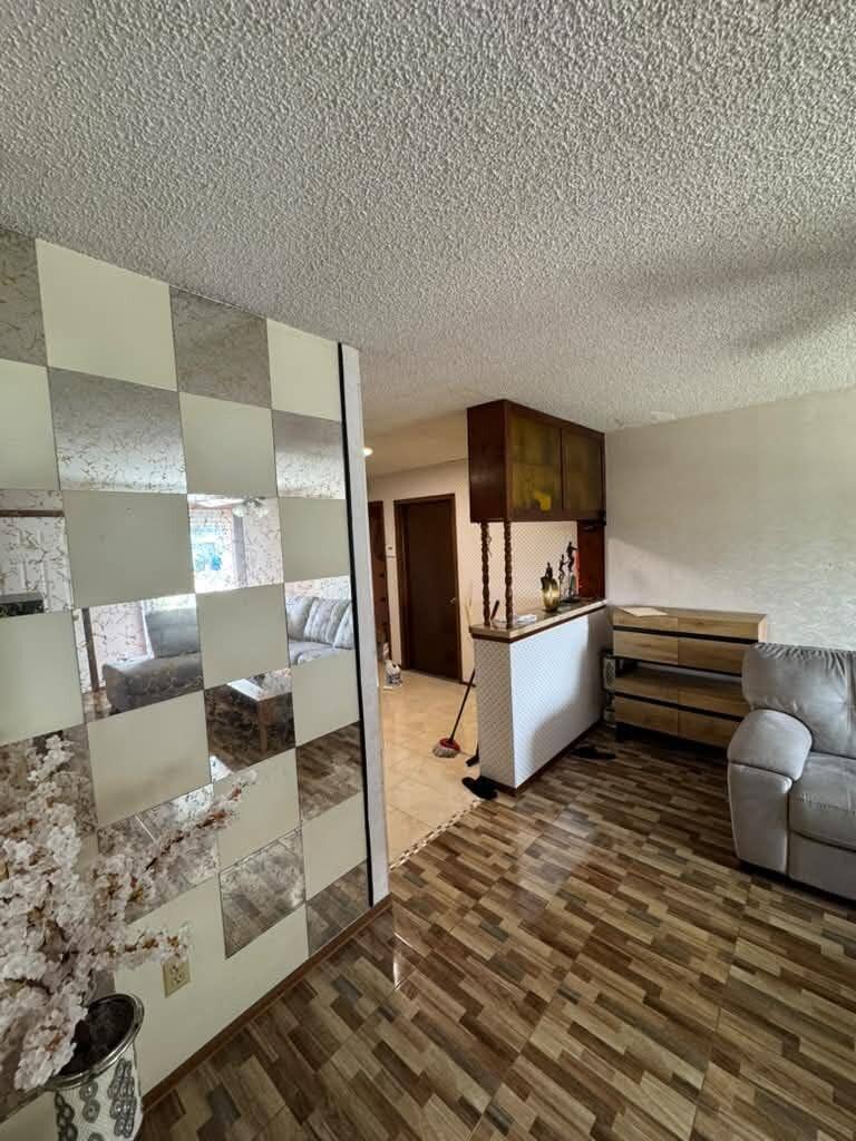 Kissimmee, FL 34744 Wood-finish flooring throughout, featuring a built-in bar with upper cabinetry and a mirrored accent wall