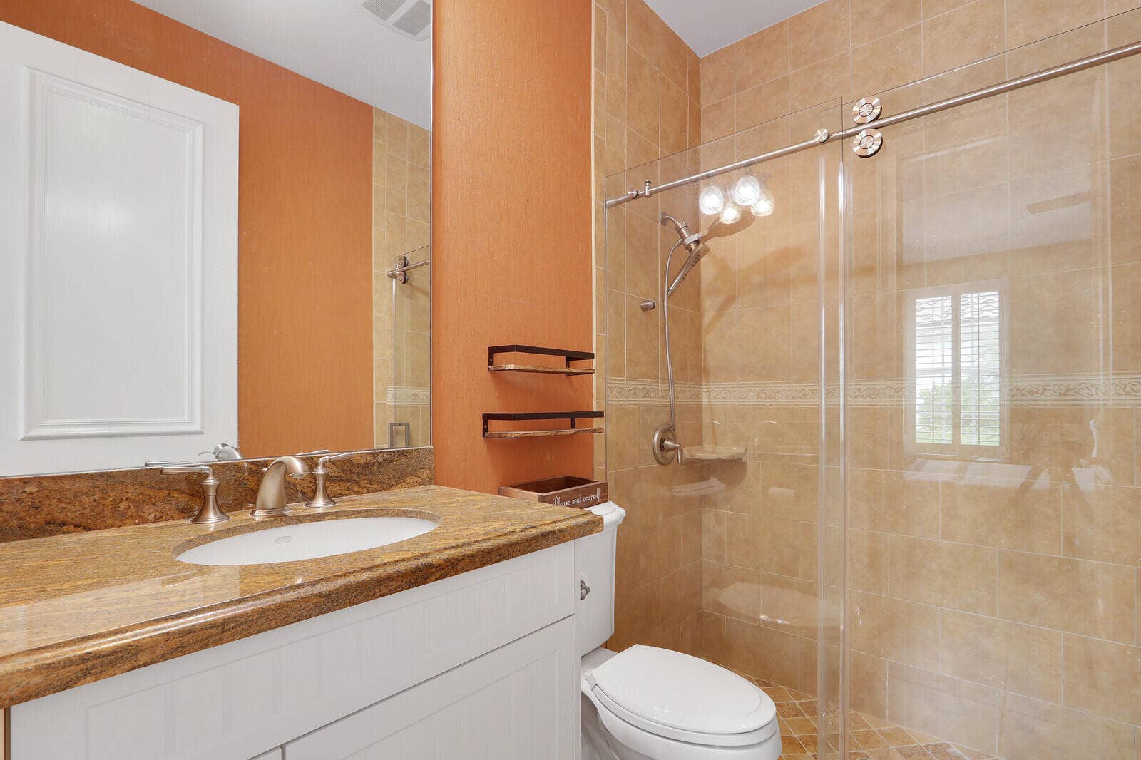 Vanity with an undermount sink and stone countertop, tile-surround shower with a glass enclosure, and a wall-mounted medicine cabinet