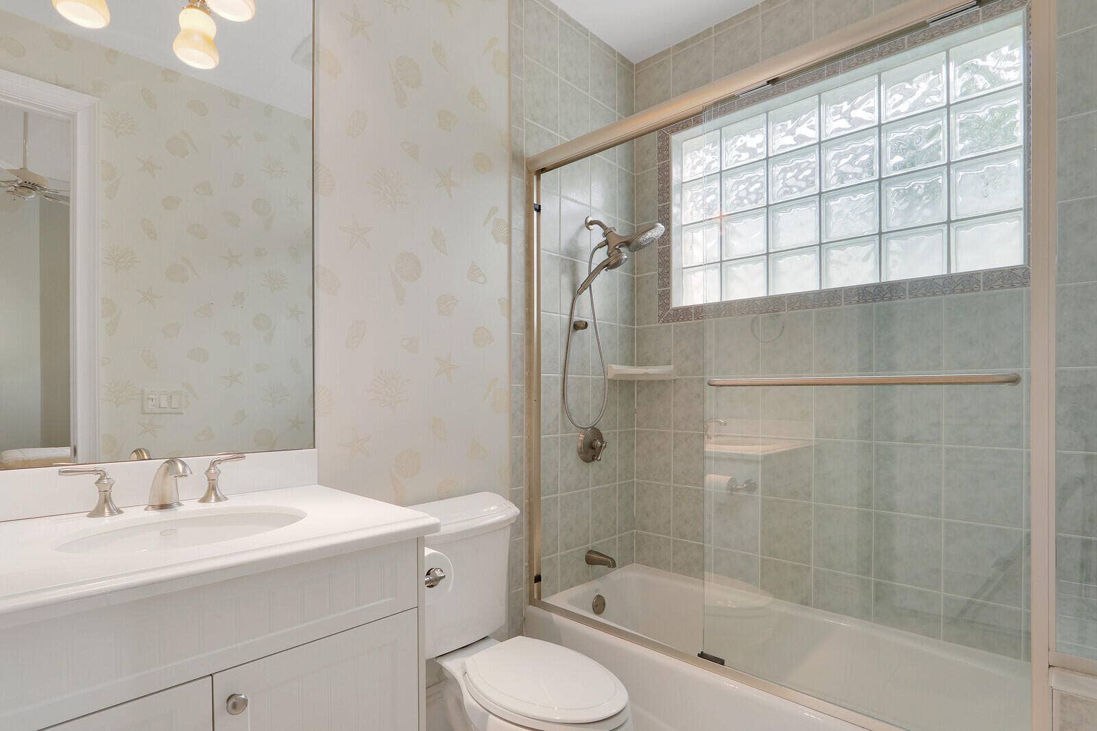 Glass-enclosed bathtub and shower combination with tile surround and glass block window