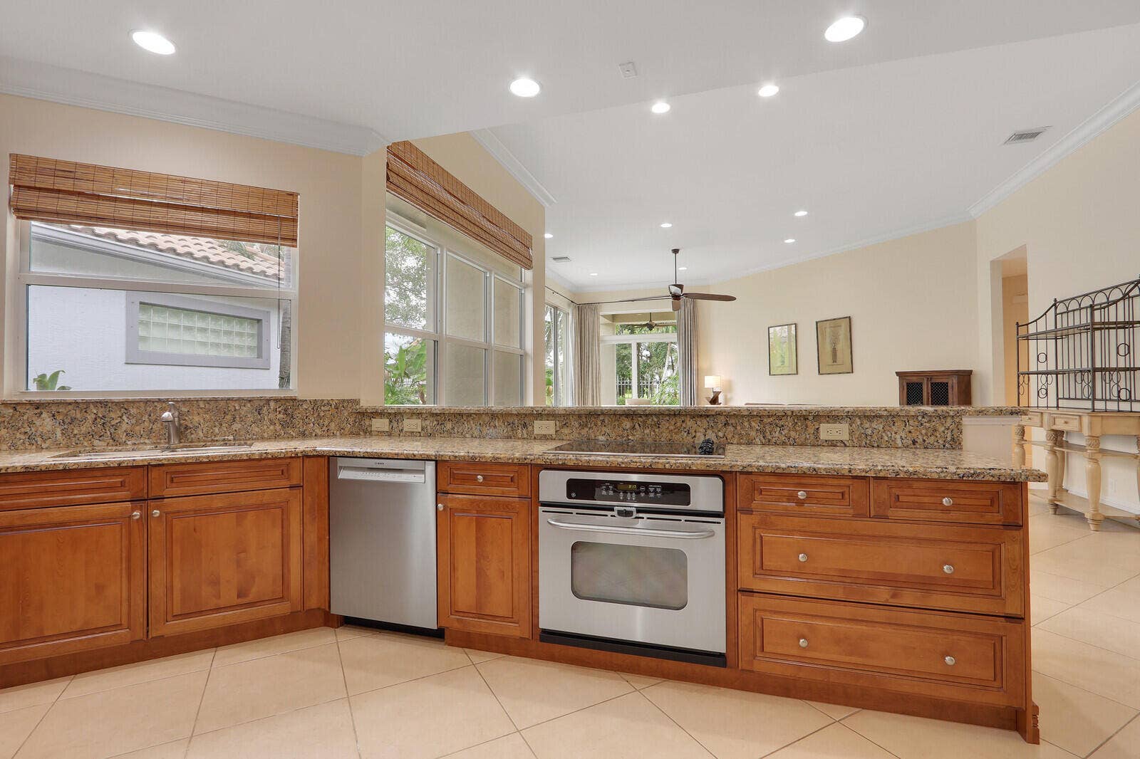 Kitchen featuring wood cabinetry, granite countertops, tile flooring, stainless steel appliances, and recessed lighting