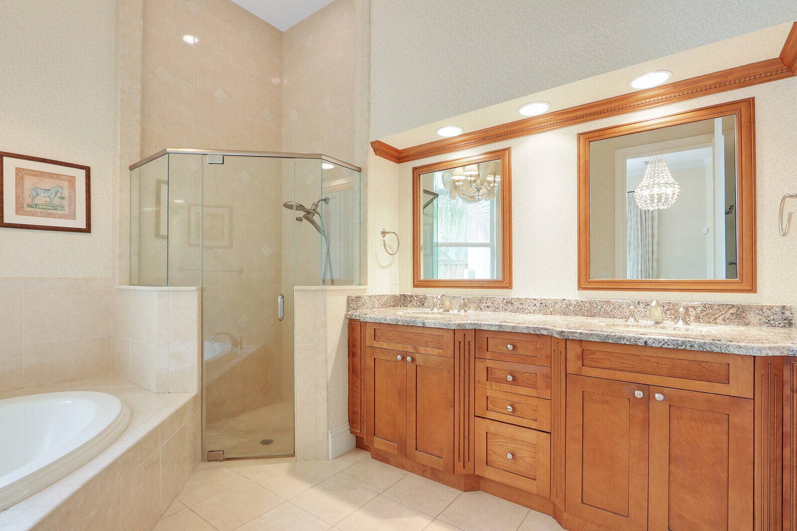 Dual vanity with wood-finish cabinetry, stone countertop, and two framed mirrors