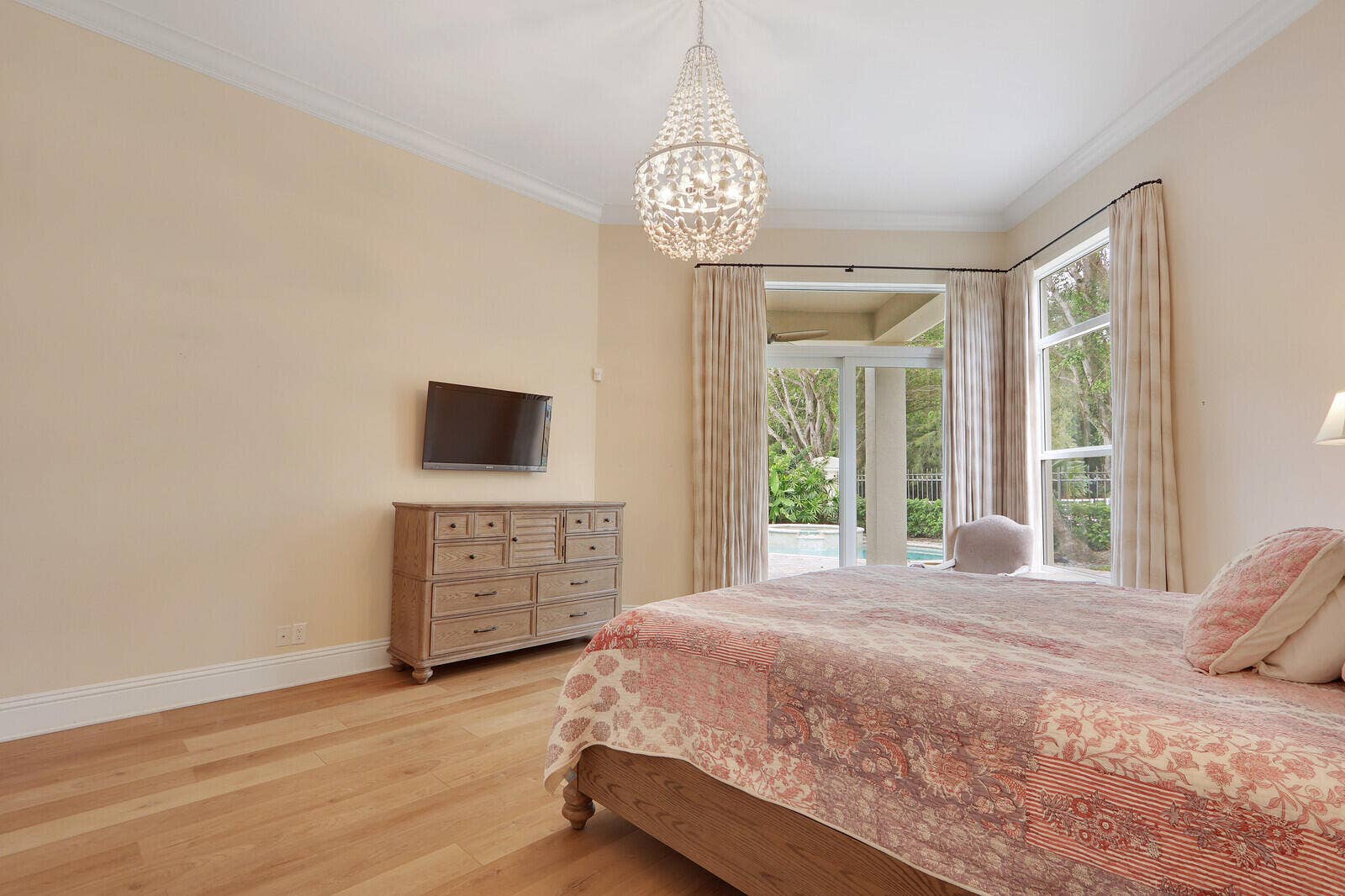 Wood-finish flooring, crown molding, and a crystal chandelier