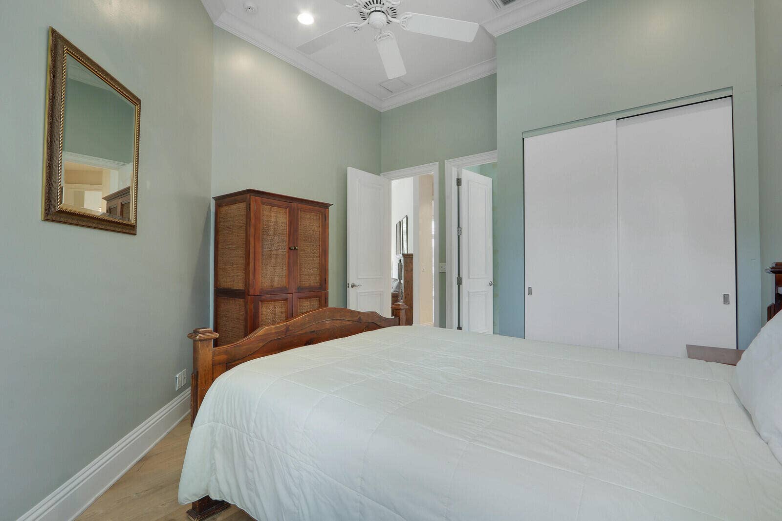 Vaulted ceilings with crown molding, ceiling fan, wood-finish flooring, and white sliding closet doors
