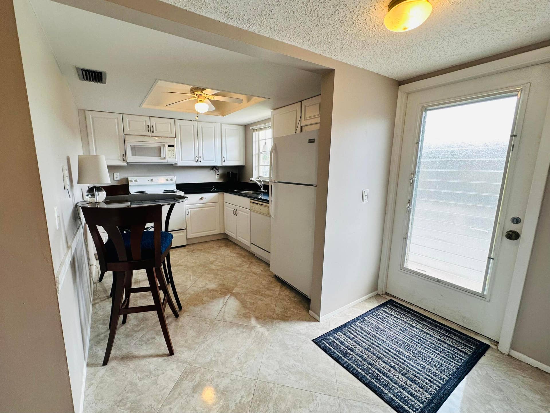 2950 SE Ocean Boulevard, #130-6, Stuart, FL 34996 Kitchen featuring white cabinetry, dark countertops, white appliances, and tile flooring
