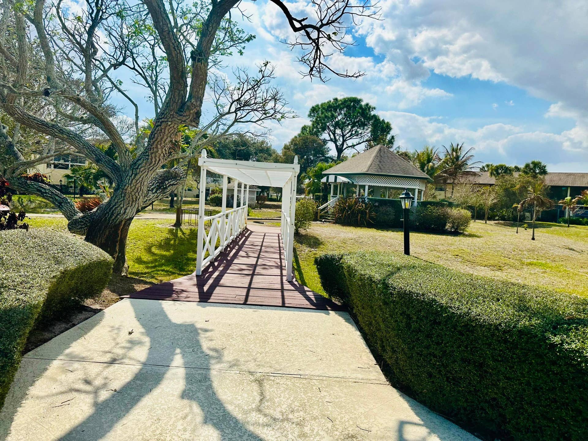 2950 SE Ocean Boulevard, #130-6, Stuart, FL 34996 Expansive landscaped grounds featuring a covered walkway, a shaded gazebo, and mature tree canopies