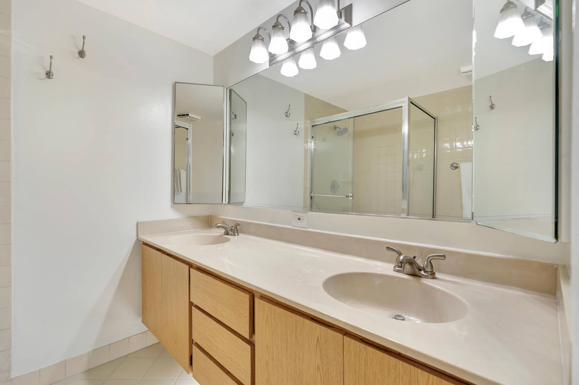 Dual vanity with integrated sinks, light wood-finish cabinetry, and brushed nickel fixtures