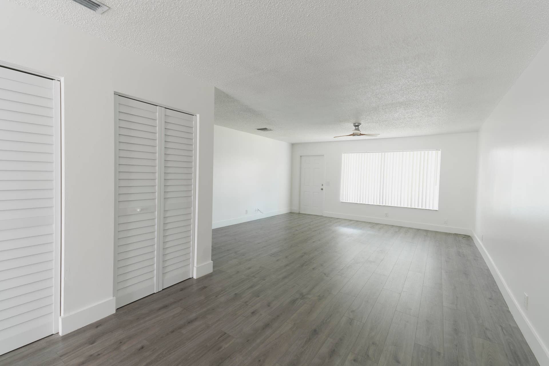 vinyl wood like flooring, white walls, louvered bi-fold doors, and a ceiling fan
