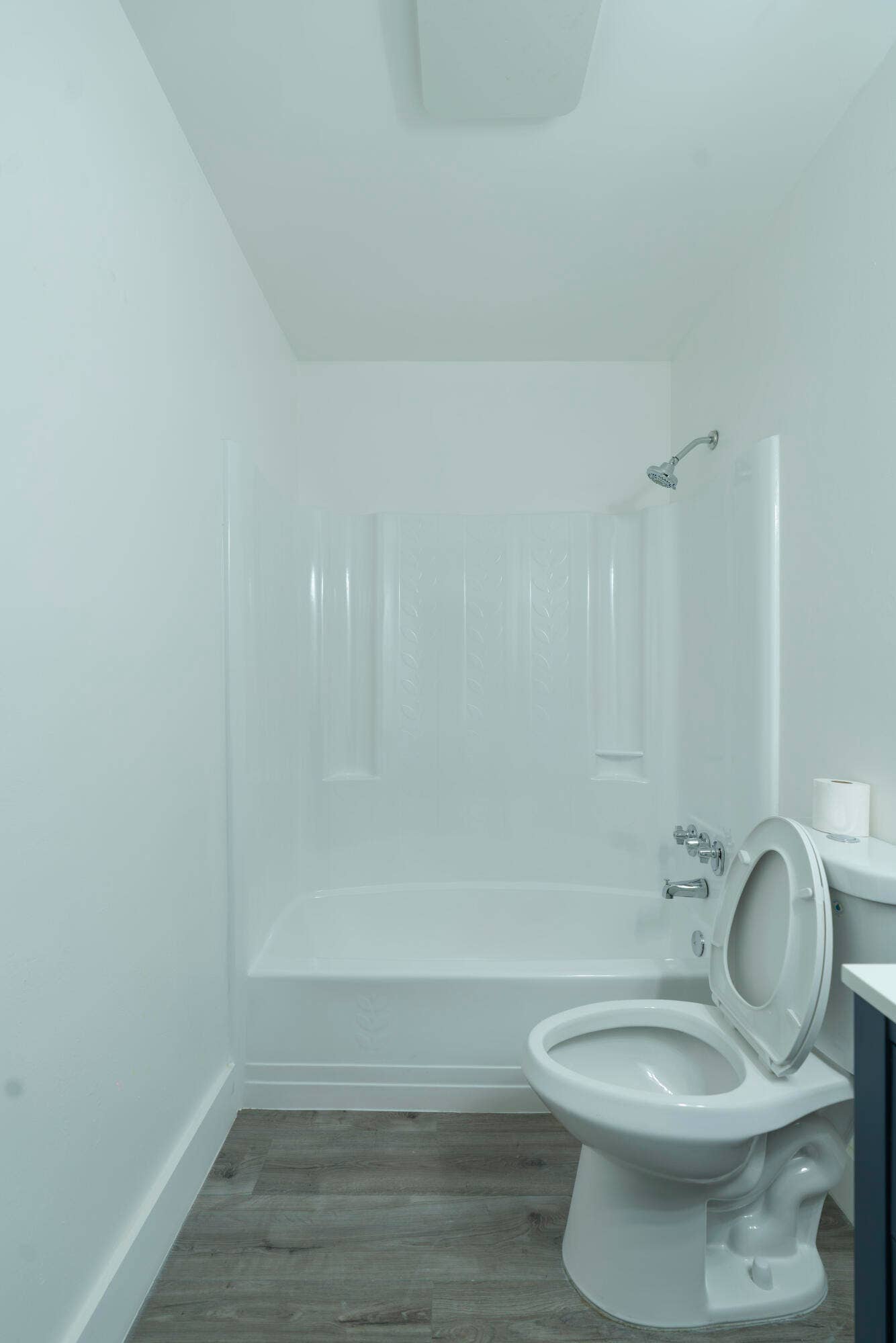 Bathroom featuring a white tub and shower combination, vinyl wood like flooring, and a white toilet