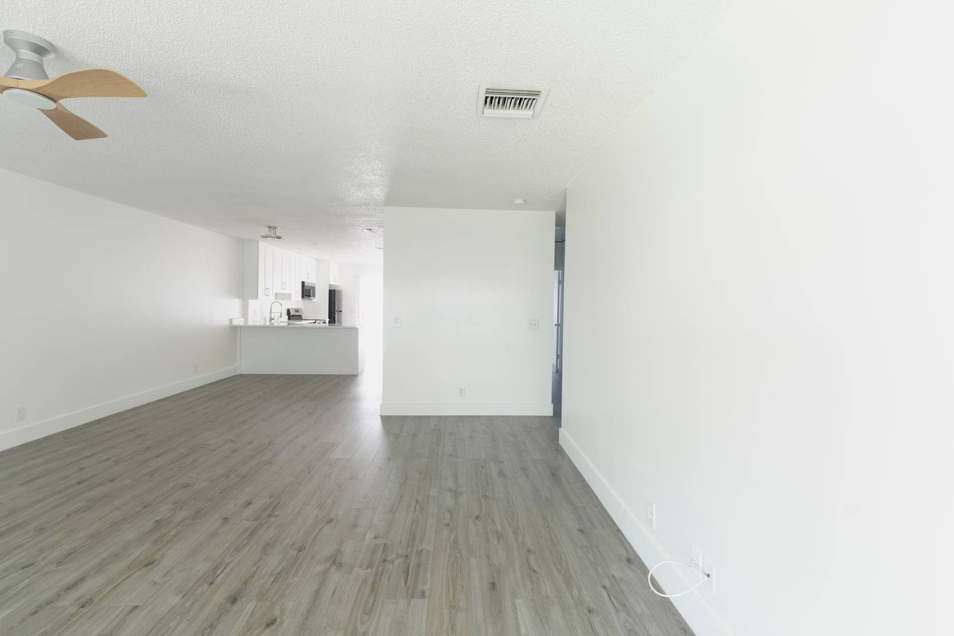 Open concept living area featuring vinyl wood like flooring, a ceiling fan, and white walls
