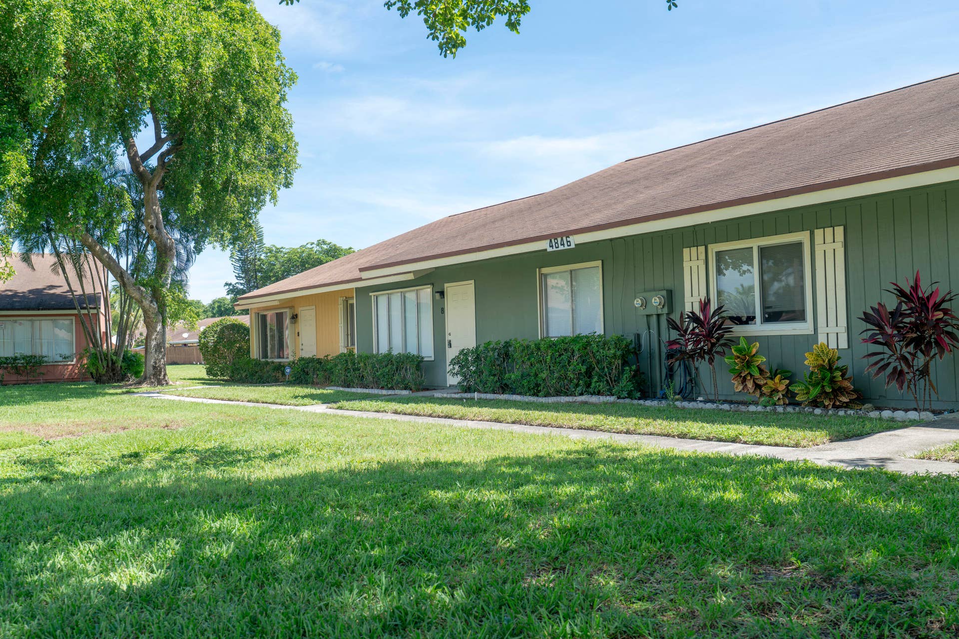Green exterior with white window shutters and a brown roof