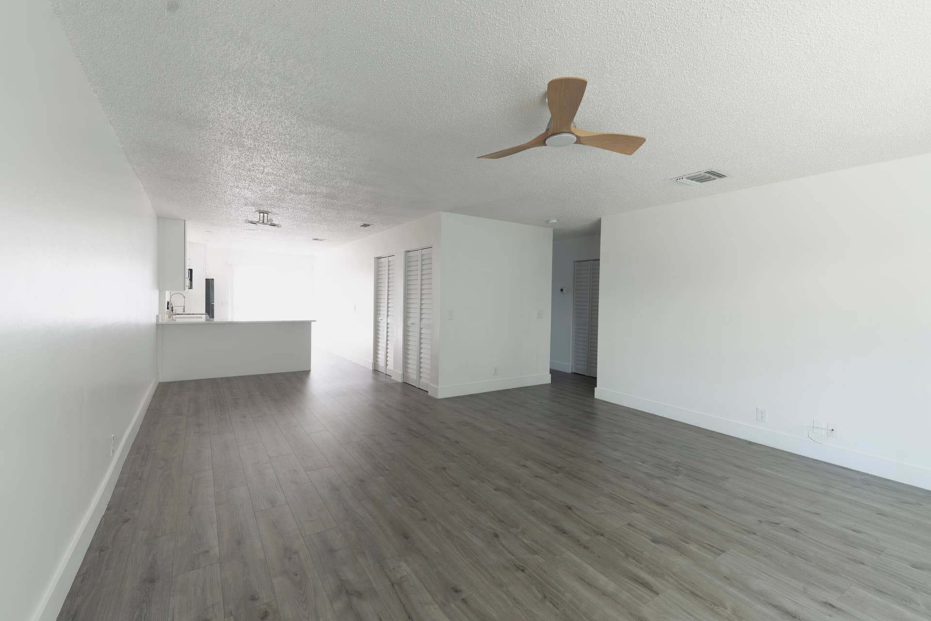 vinyl wood like flooring throughout, white walls, and a contemporary ceiling fan