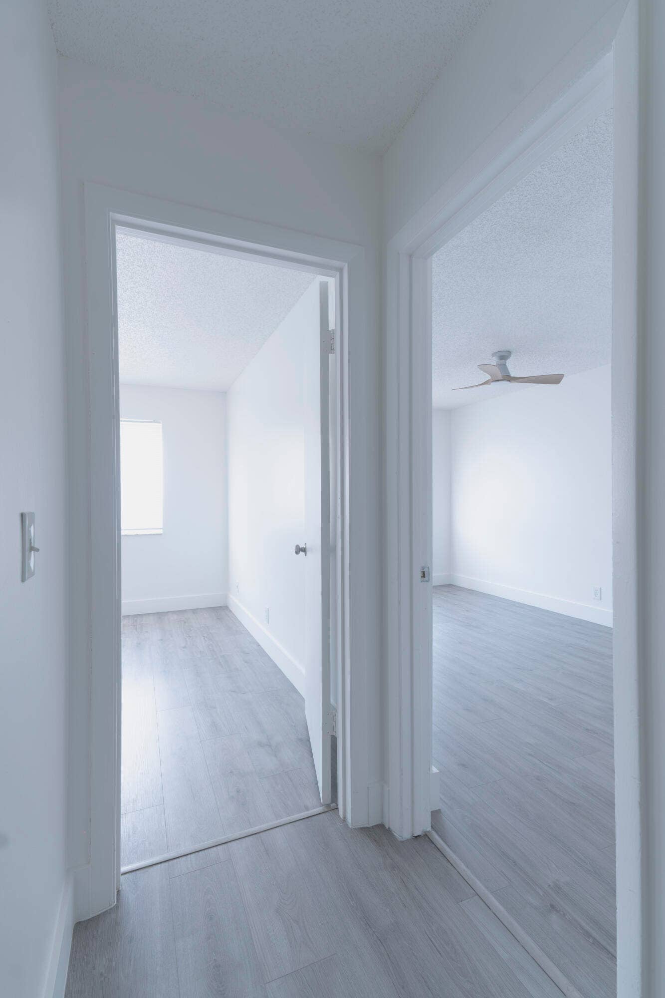vinyl wood like flooring throughout, bright white walls, and a ceiling fan