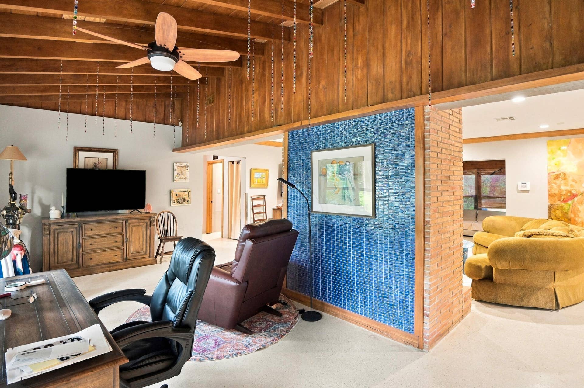 1549 SW 30th Place, Fort Lauderdale, FL 33315 Vaulted wood-paneled ceiling with exposed beams, illuminated ceiling fan, blue mosaic tile wall accent, and interior brick column