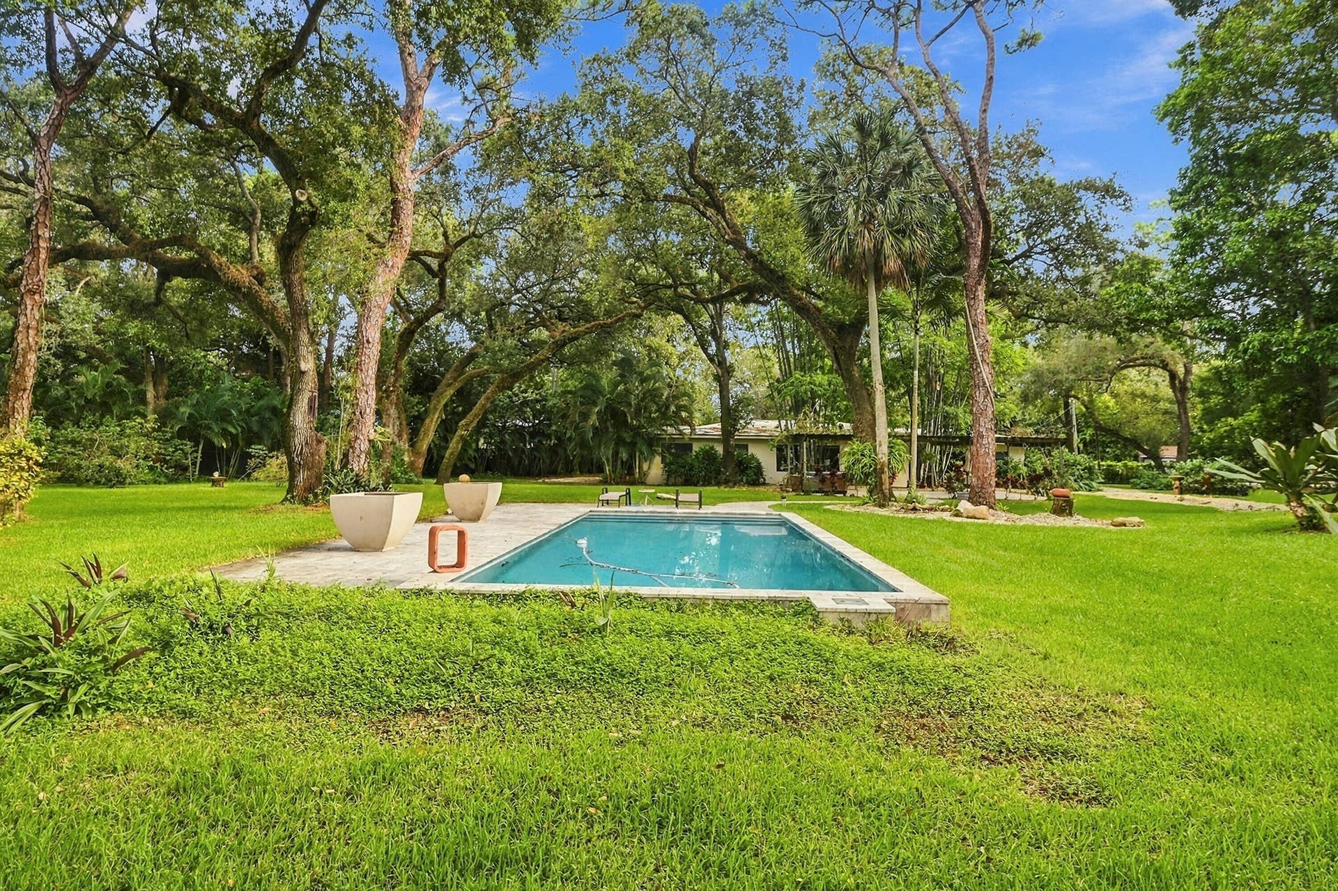 1549 SW 30th Place, Fort Lauderdale, FL 33315 Rectangular swimming pool with a surrounding hardscape patio, bordered by extensive lawn areas and mature trees