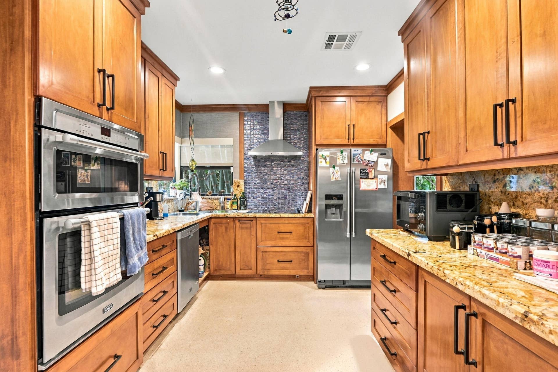 1549 SW 30th Place, Fort Lauderdale, FL 33315 Wood-finish cabinetry, stainless steel double oven, stainless steel French door refrigerator, granite countertops, and mosaic tile backsplash