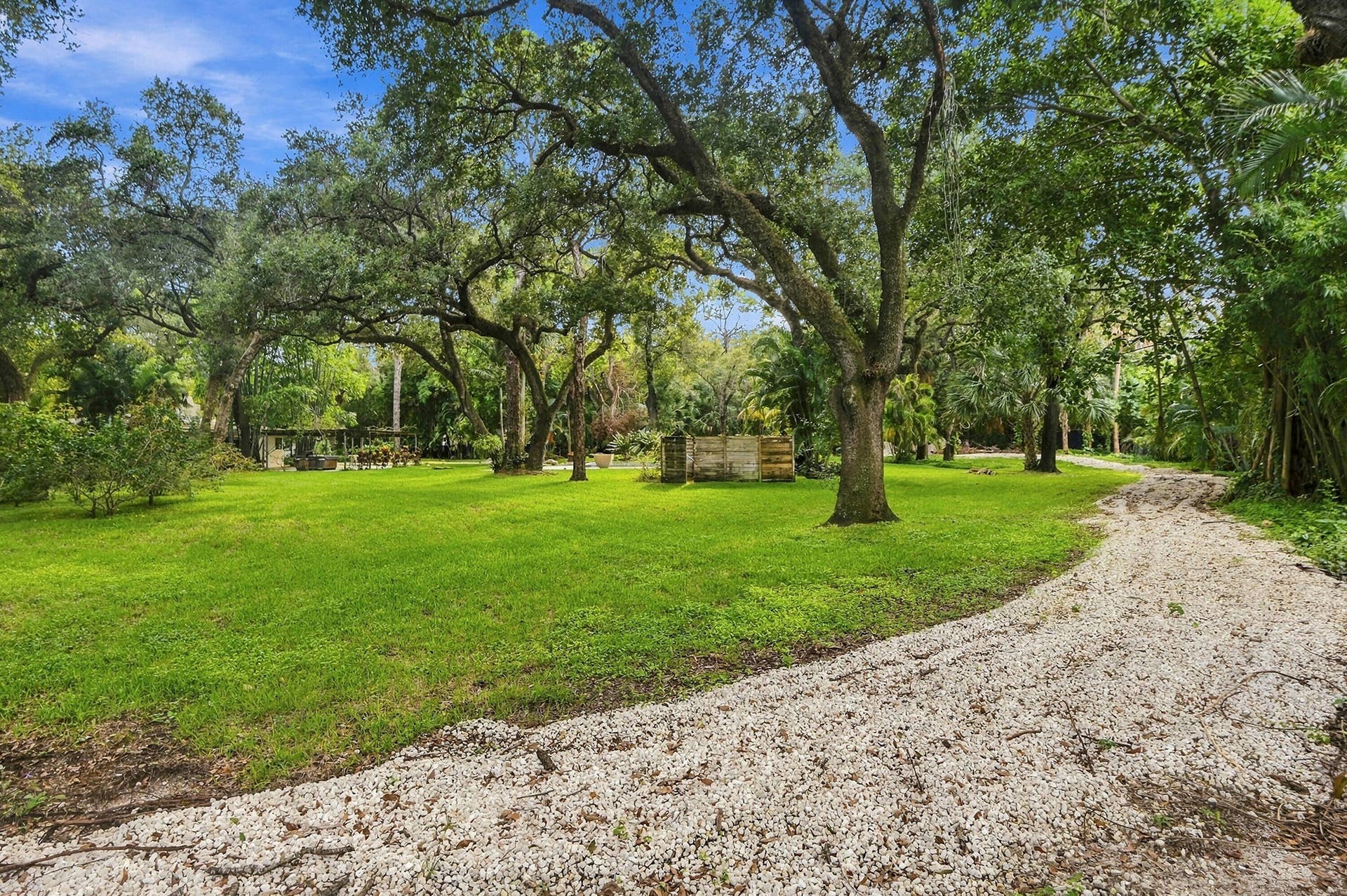 1549 SW 30th Place, Fort Lauderdale, FL 33315 Expansive green lawn with mature trees and a gravel driveway